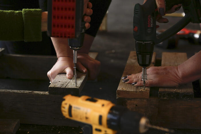 two people screwing wooden planks, on the picture you only see the drill machines and two hands