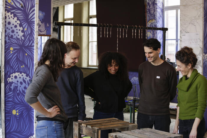 Five people looking at a wooden piece of furniture